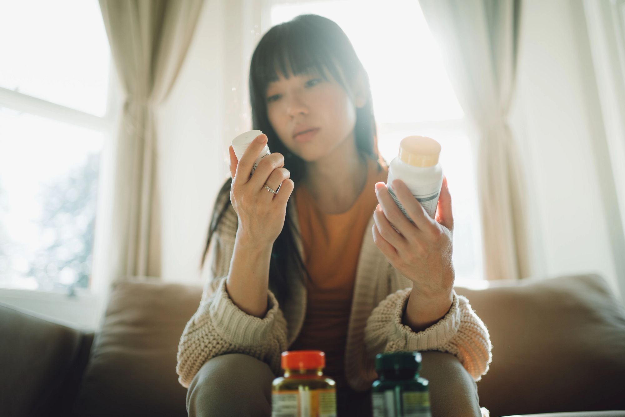 Asian woman choosing between supplements.