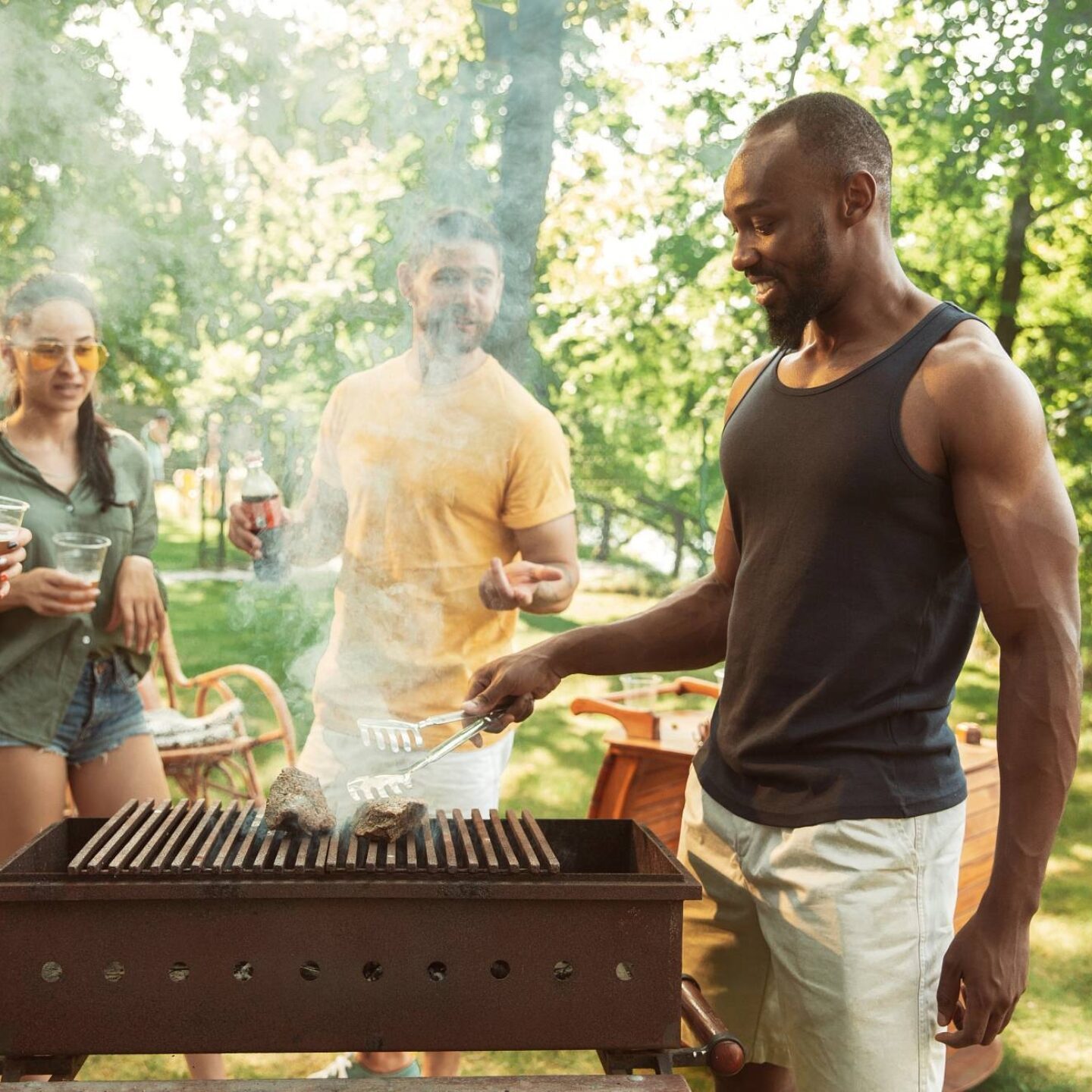 A group of friends enjoying a barbecue party together - Bring the Backyard BBQs Back: 8 Safety Tips for Summer Food | NSF