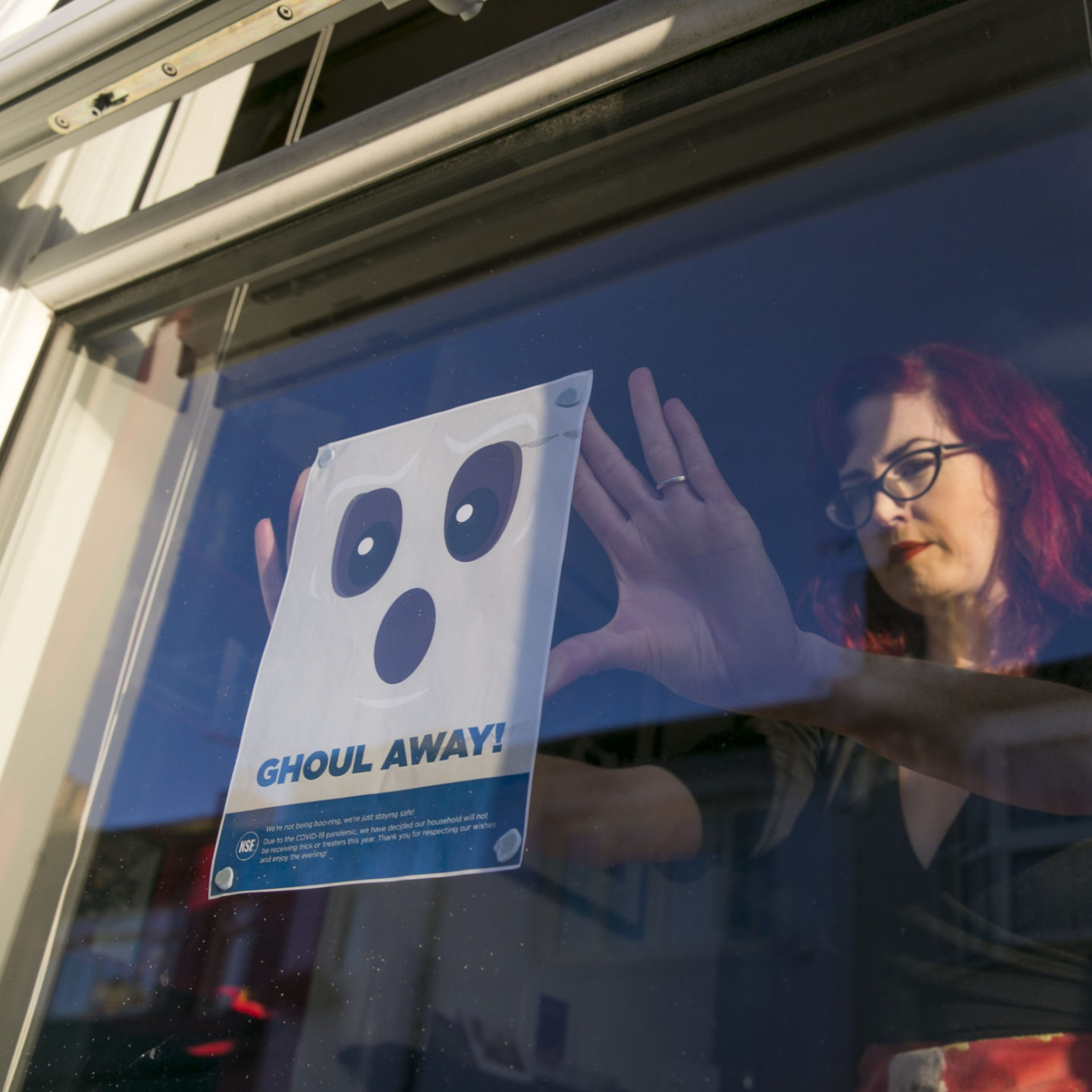 Woman hanging NSF Halloween poster in window