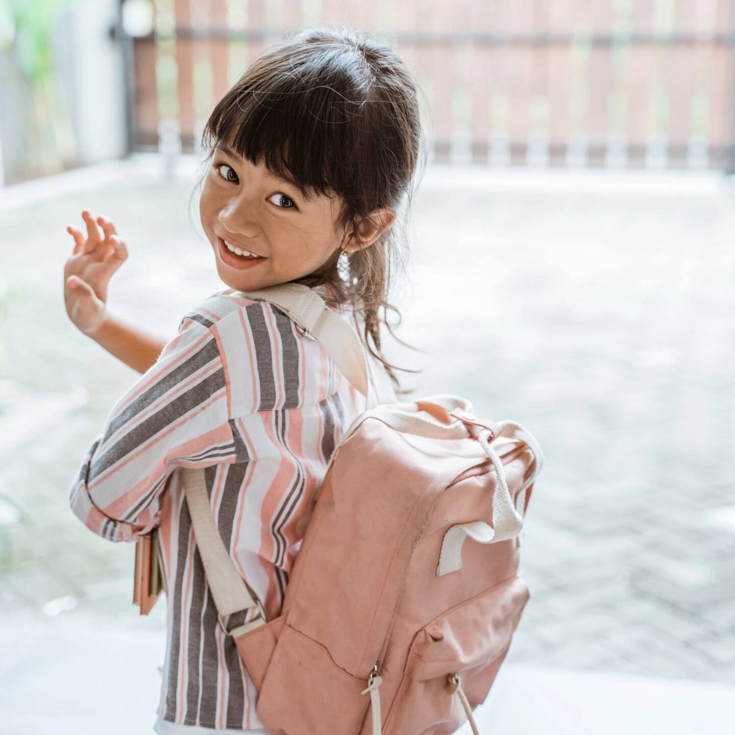 A girl waving goodbye before leaving for school - Back-to-School Season 2022: Prepping Your Kids for Safety | NSF