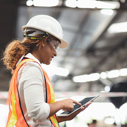 Female worker wearing helmet looking at the tablet in factory facility - CMMC Overview Program for DoD | NSF-ISR